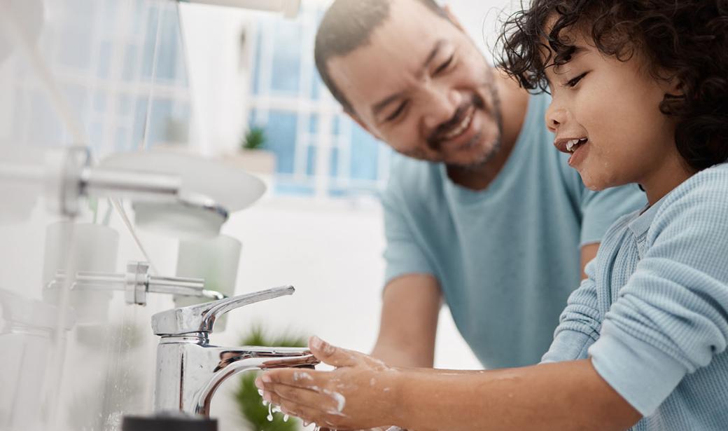 A father teaching his son how to wash his hands.