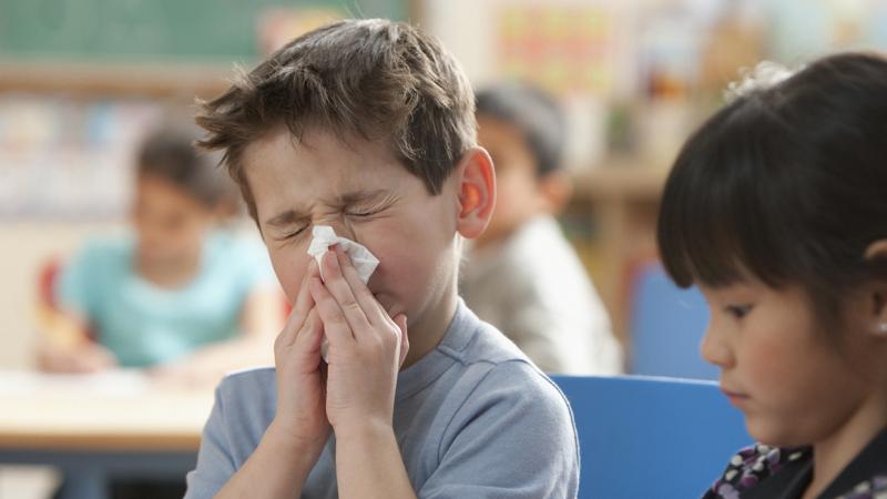 young boy blowing his nose