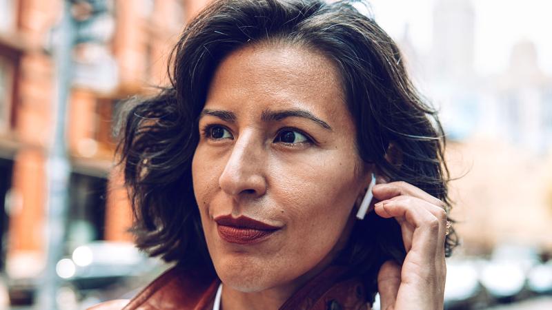A woman outdoors wearing earbuds.