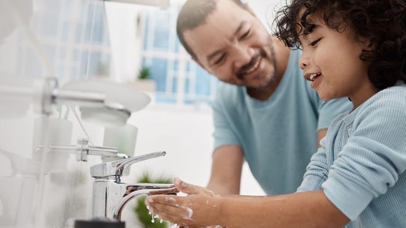 A father teaching his son how to wash his hands.