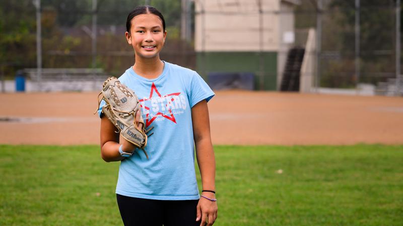 A smiling photo of Arielle with on a softball glove on. 