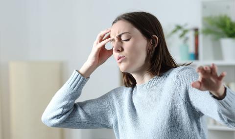 A woman holding her head, reaching out to prevent a fall.